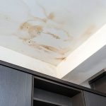 Image of ceiling stains indicating water damage above wooden cabinetry in a home serviced by Quahog Plumbing.