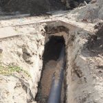 Exposed pipeline in trench at construction site, showcasing plumbing infrastructure work by Quahog Plumbing.