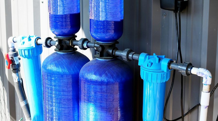 Water filtration system with two large blue tanks and pipes, by Quahog Plumbing, ensuring efficient water quality solutions.