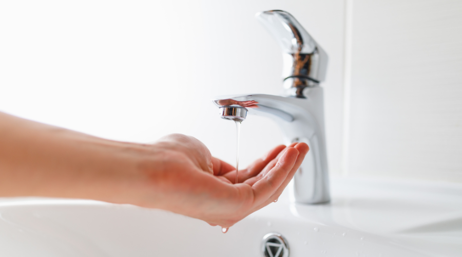 Hand receiving water from a modern faucet, illustrating issues related to low water pressure in plumbing systems.