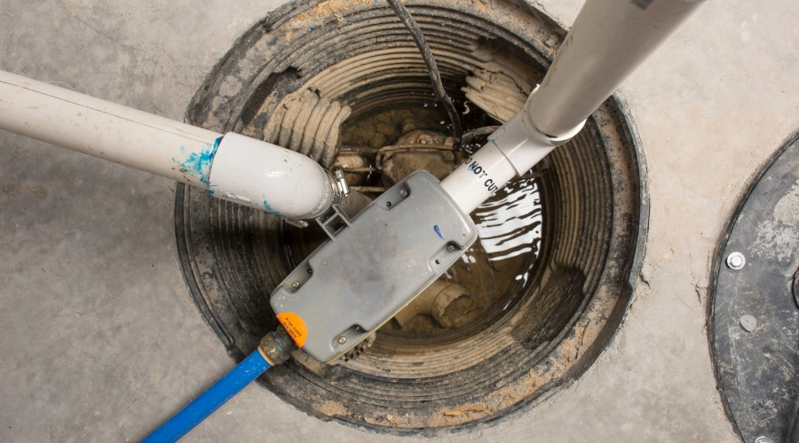 Sump pump installation in a basement, showcasing the pump and discharge pipes, relevant to flood prevention and water damage protection.